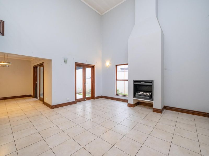 Spacious living room featuring high vaulted ceilings, tiled flooring, and a built-in fireplace, offering a bright and open layout.