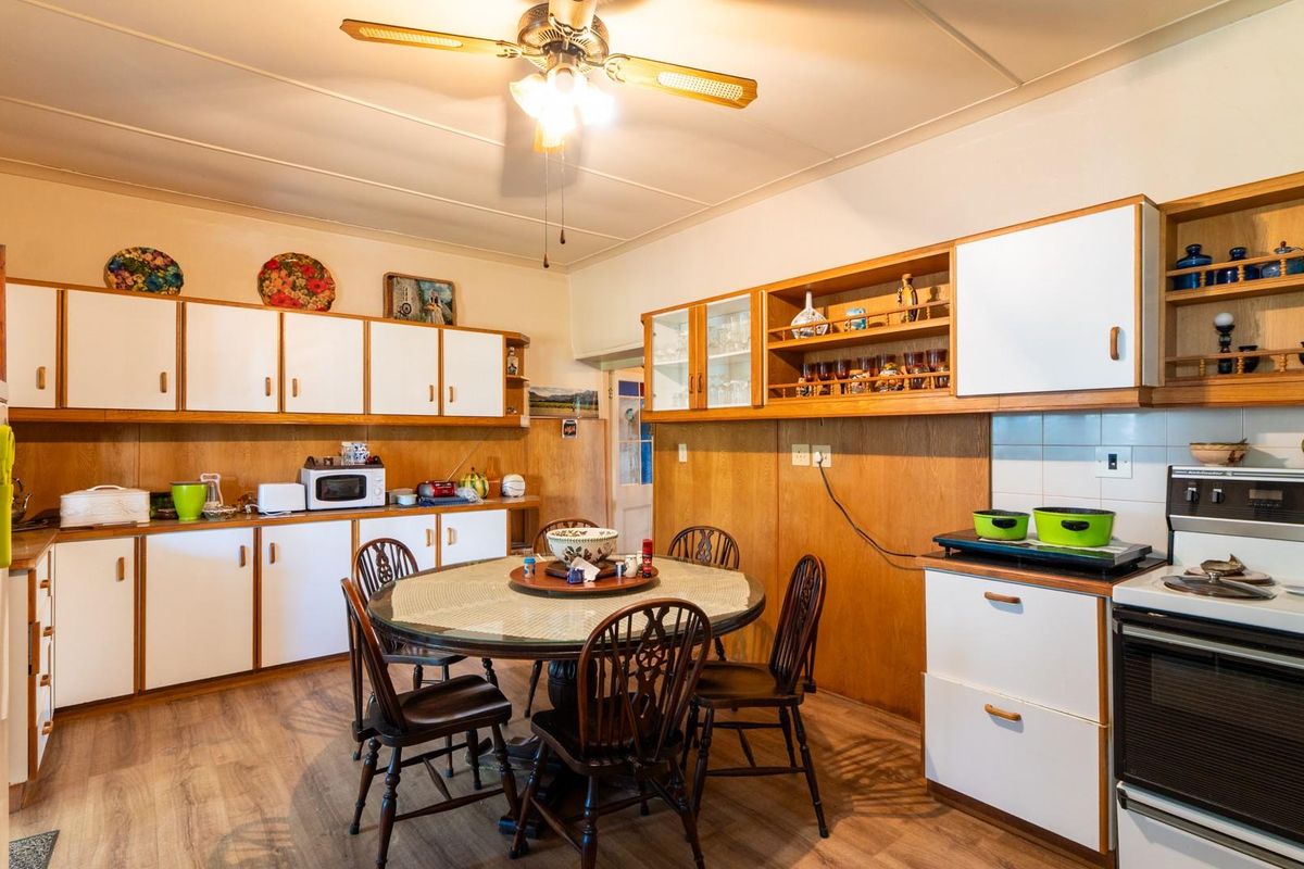 A spacious kitchen featuring extensive built-in cabinetry, a ceiling fan, and a freestanding oven, offering a functional layout with potential for modern updates.