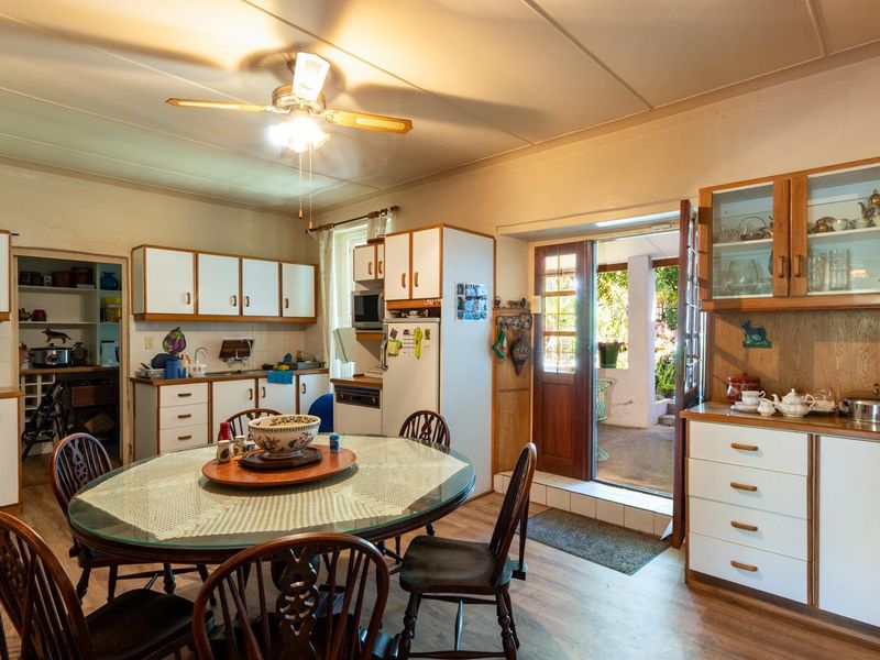 Open-plan kitchen and dining area featuring dated cabinetry, laminate flooring, and direct access to an outdoor patio space.