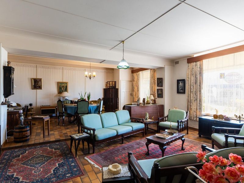 Spacious open-plan living and dining area featuring tiled flooring, panelled walls, and large windows providing ample natural light.