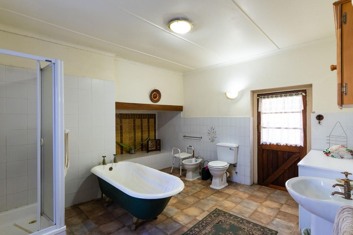 Spacious bathroom featuring a freestanding bathtub, separate shower enclosure, bidet, toilet, and pedestal sink with classic tiled finishes.