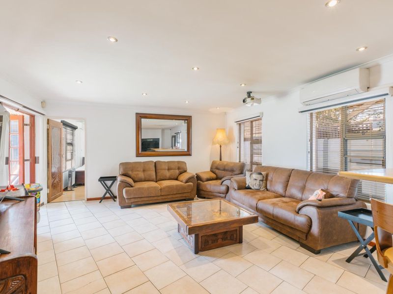 Spacious living room featuring ceramic tiled flooring, recessed downlighting, and a wall-mounted split-system air conditioner.