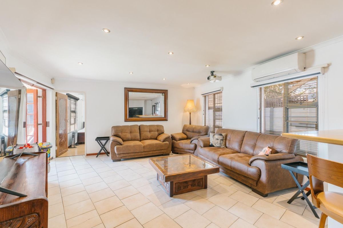 Spacious living room featuring ceramic tiled flooring, recessed downlighting, and a wall-mounted split-system air conditioner.