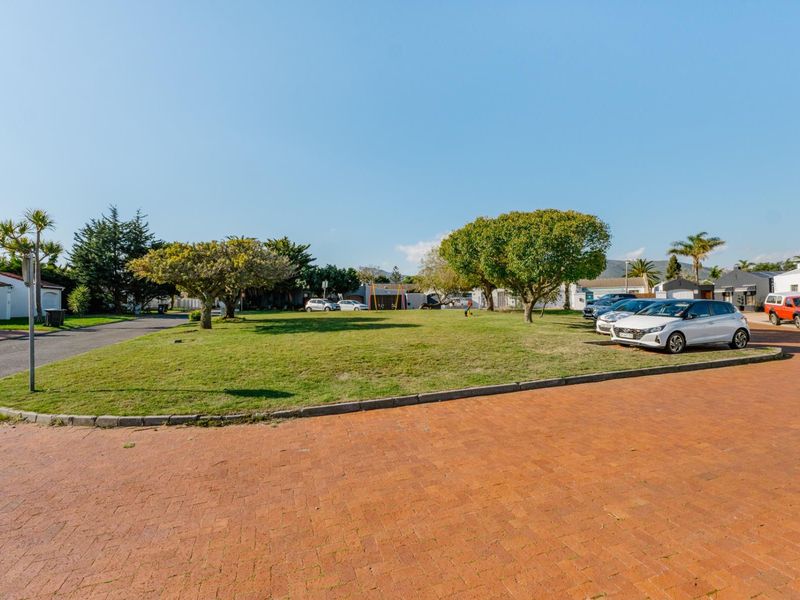 A view of the residential street featuring a paved driveway, well-maintained lawn, and mature trees within the estate grounds.