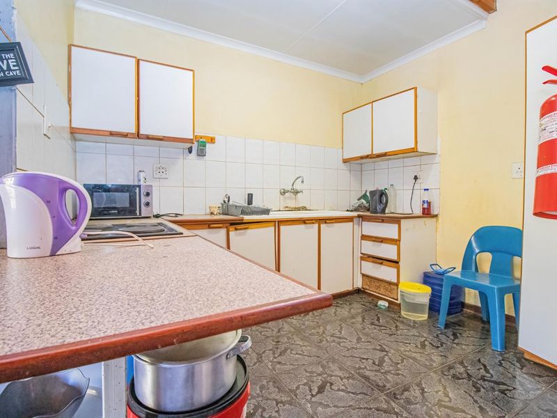A functional kitchen featuring laminate countertops, tiled backsplash, and built-in cabinetry, offering a practical layout with potential for modern cosmetic updates.
