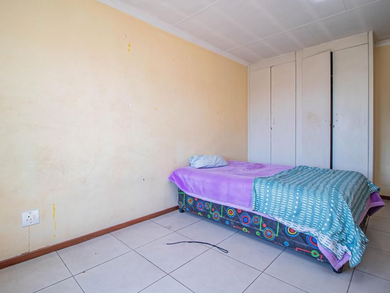 A bedroom featuring tiled flooring and built-in cupboards, requiring cosmetic updates to the wall finishes to improve the overall aesthetic.