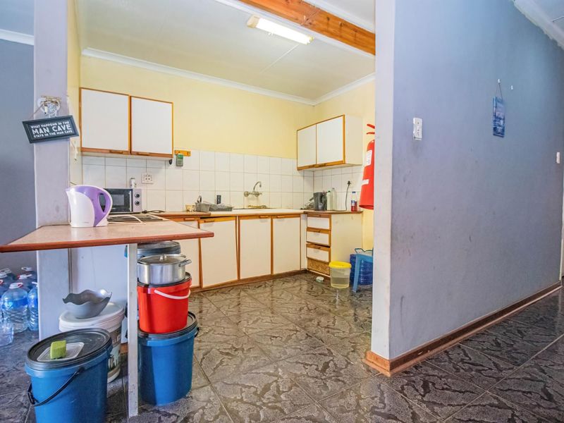 A functional kitchen area featuring built-in cabinetry, a tiled backsplash, and tiled flooring, offering potential for modernization and aesthetic updates.