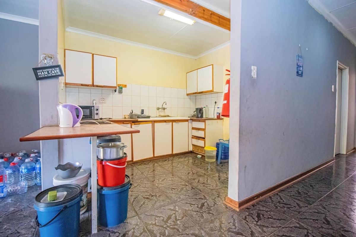 A functional kitchen area featuring built-in cabinetry, a tiled backsplash, and tiled flooring, offering potential for modernization and aesthetic updates.