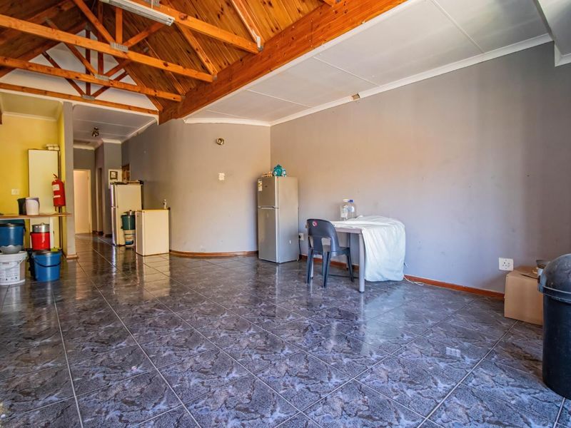 Open plan living area featuring exposed timber roof trusses and tiled flooring, offering a versatile space for customization.