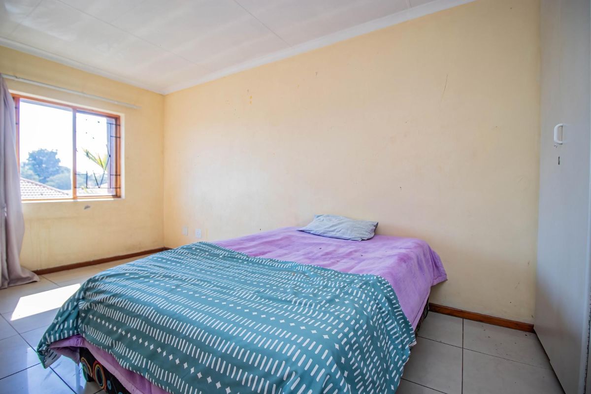A bedroom featuring tiled flooring, a built-in cupboard, and a window with security bars, requiring minor cosmetic updates to the walls.