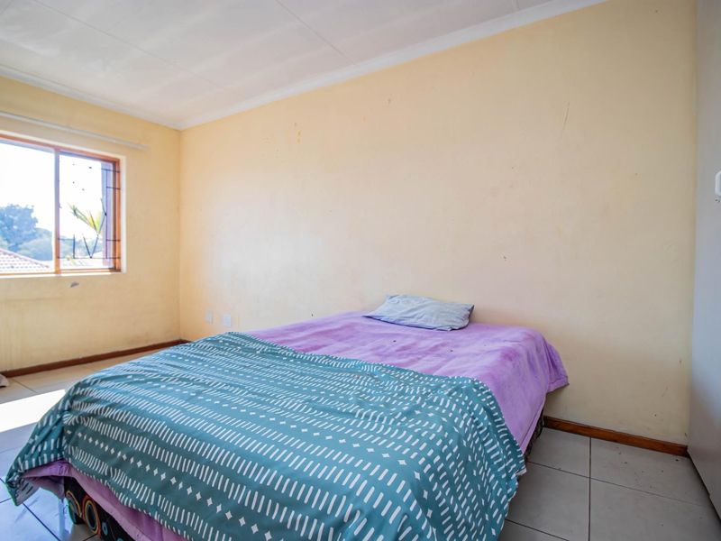 A bedroom featuring tiled flooring, a built-in cupboard, and a window with security bars, requiring minor cosmetic updates to the walls.