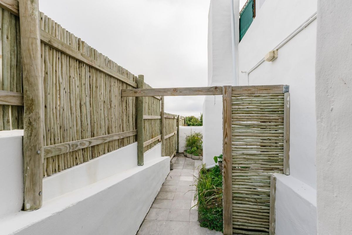 A narrow, private side passage featuring tiled flooring and timber pole fencing, providing a clean and functional outdoor transition area.