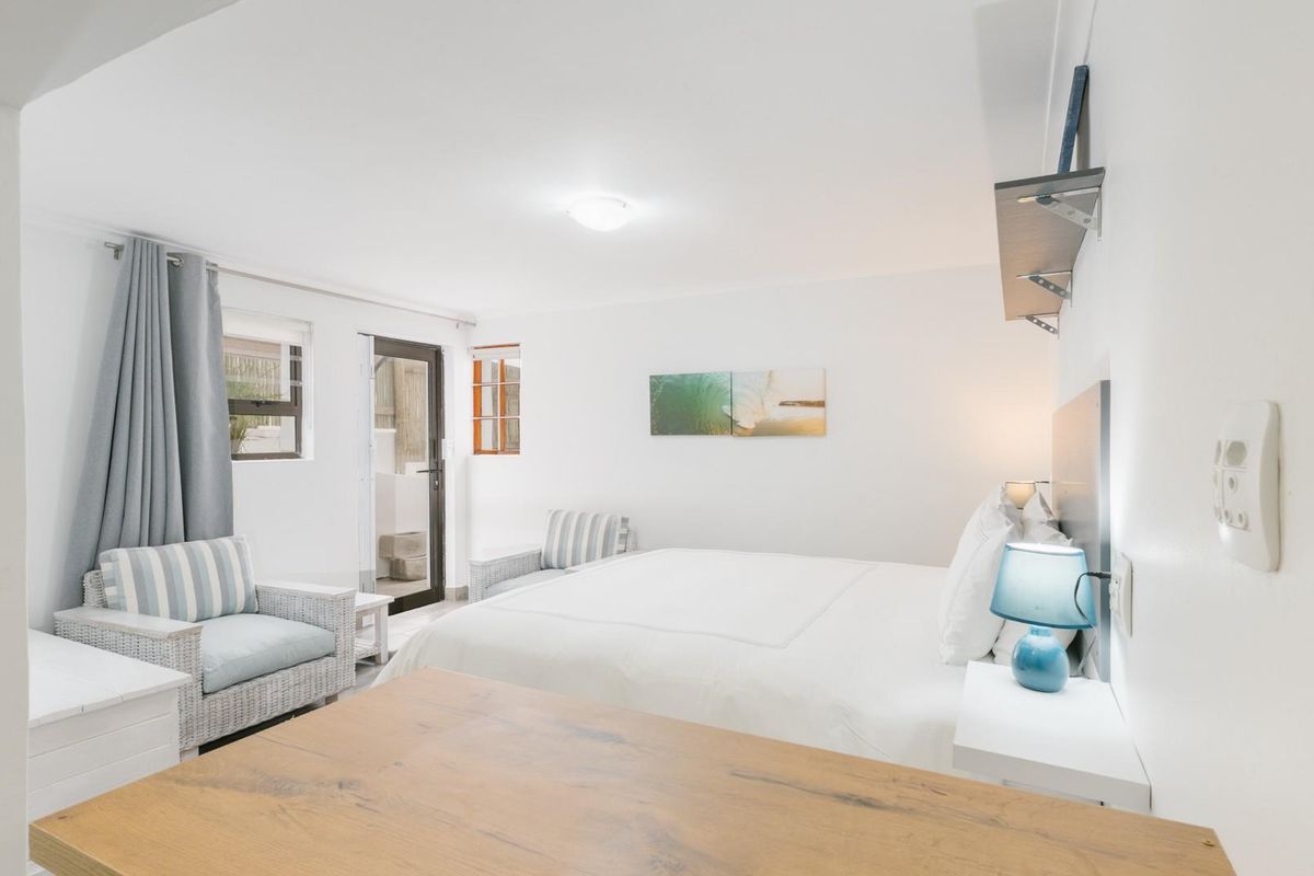 A bright and well-maintained bedroom featuring neutral finishes, built-in shelving, and direct access to an outdoor area through a glass door.