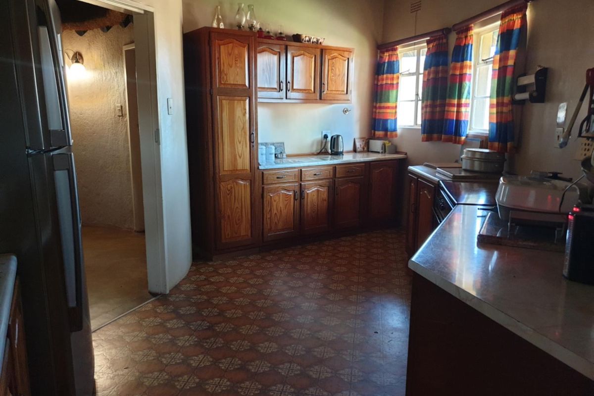 A functional kitchen featuring traditional wooden cabinetry, laminate countertops, and patterned floor tiles, offering a classic farm-style aesthetic with potential for modern updates.