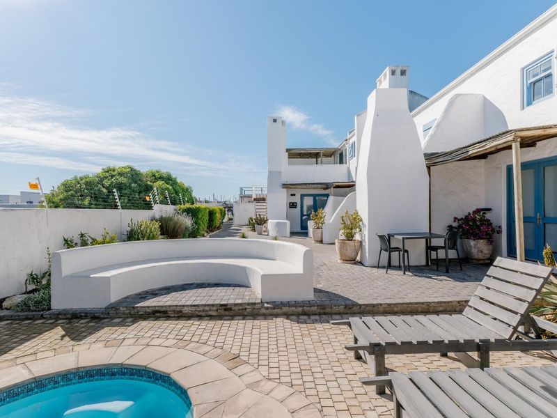 A well-maintained outdoor pool area featuring a paved patio, built-in curved bench, and an outdoor fireplace, perfect for relaxation and entertaining.