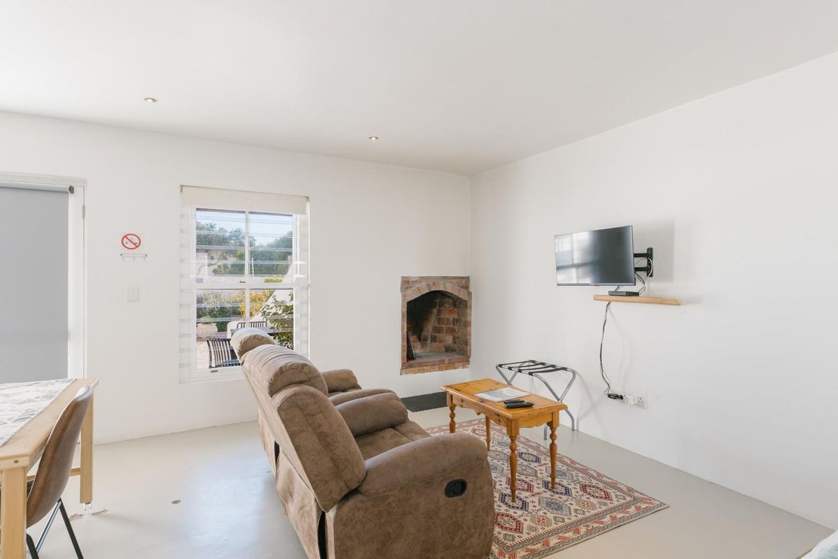 A bright living area featuring a traditional brick fireplace, neutral flooring, and direct access to the outdoor space through a sliding door.
