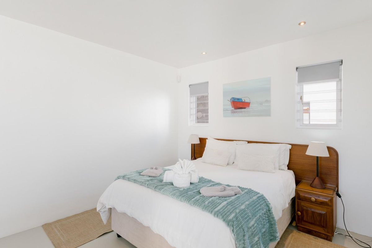 A bright and well-maintained bedroom featuring recessed downlighting, neutral finishes, and functional louvre windows.