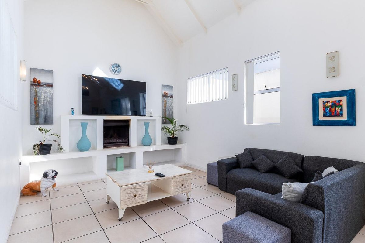 Bright living room featuring a vaulted ceiling, tiled flooring, and a built-in fireplace with integrated shelving units.