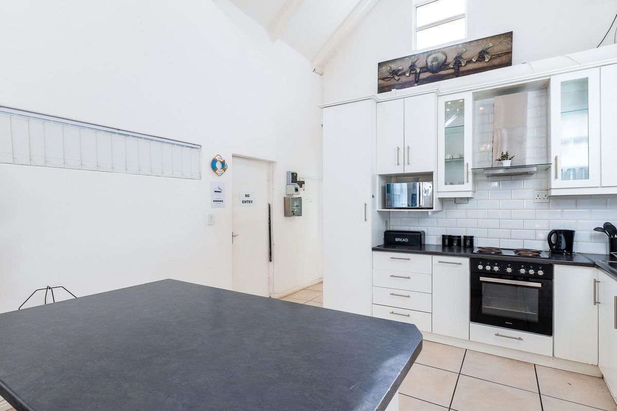 A bright kitchen featuring white cabinetry, subway tile backsplash, built-in appliances, and a high vaulted ceiling with tiled flooring.