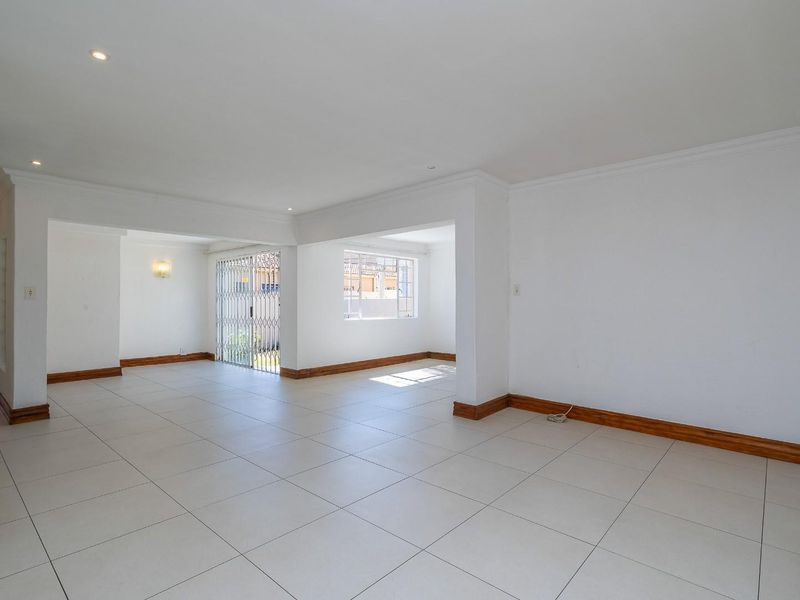 A spacious, open-plan living area featuring neutral tiled flooring, recessed downlighting, and clean white walls, providing a versatile blank canvas for interior design.
