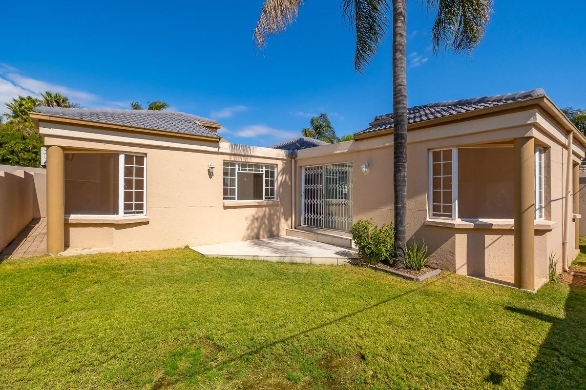 Rear view of the house featuring a paved patio area, well-maintained lawn, and secure sliding door access.