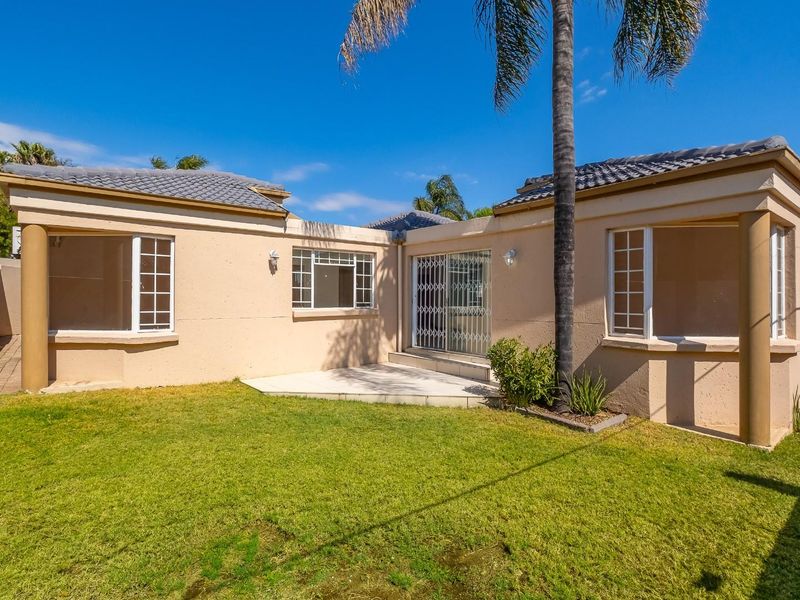 Rear view of the house featuring a paved patio area, well-maintained lawn, and secure sliding door access.