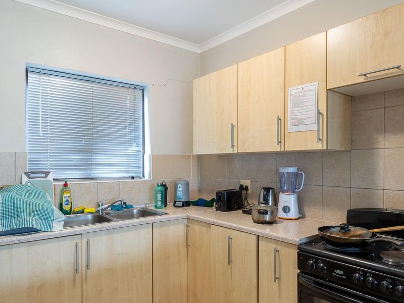 Functional kitchen featuring light wood-finish cabinetry, laminate countertops, tiled backsplash, and a freestanding stove, with a window providing natural light.