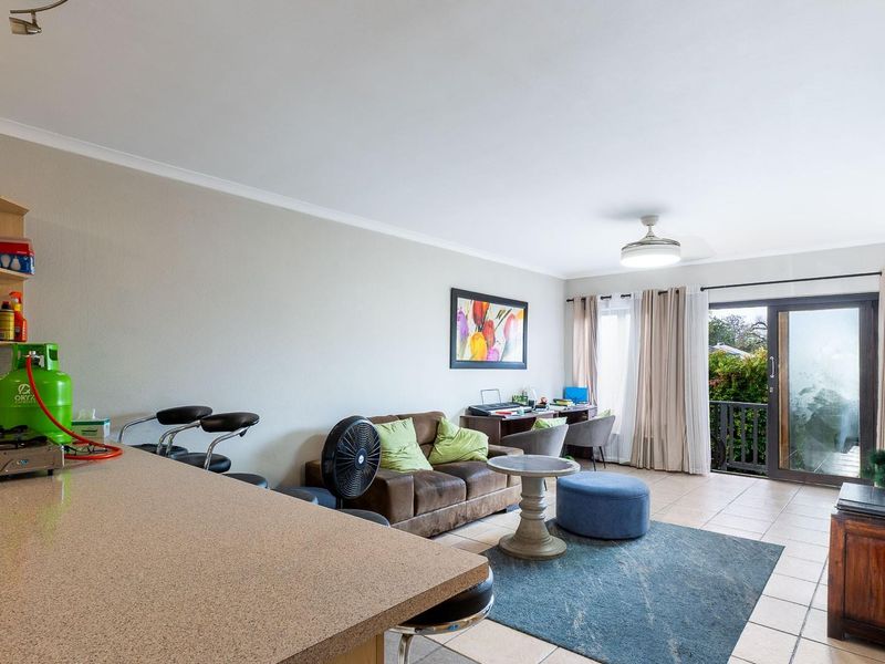 Open-plan living area featuring a breakfast bar, tiled flooring, and a sliding glass door providing access to an outdoor space.