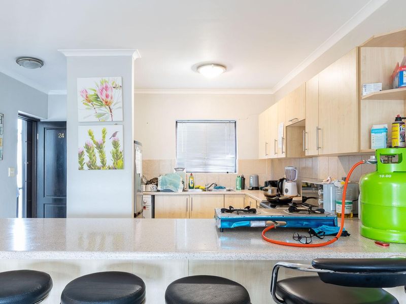 A functional kitchen featuring laminate cabinetry, a tiled backsplash, and a breakfast bar counter, providing a practical layout for daily meal preparation.