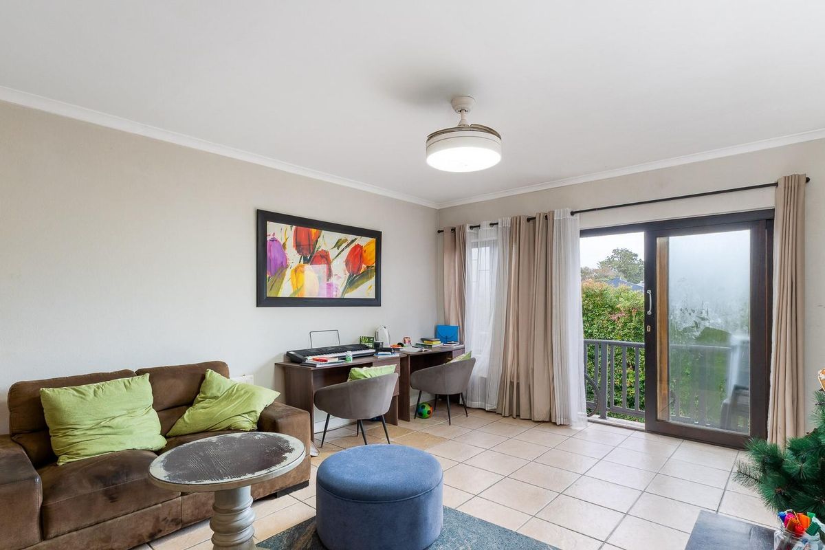 A living room featuring ceramic floor tiles, a ceiling fan, and a sliding glass door providing access to an outdoor balcony area.