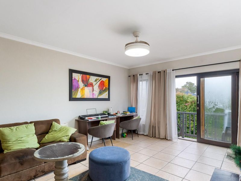 A living room featuring ceramic floor tiles, a ceiling fan, and a sliding glass door providing access to an outdoor balcony area.