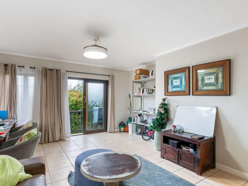 A living room featuring tiled flooring, a ceiling fan, and a sliding glass door providing access to an outdoor balcony area.