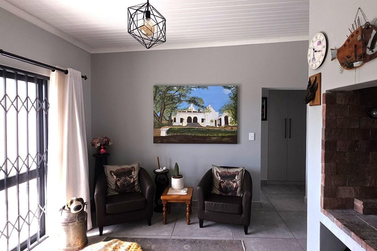 A living room featuring a built-in brick fireplace, tiled flooring, and a decorative pendant light, with access to an outdoor area via a security gate.