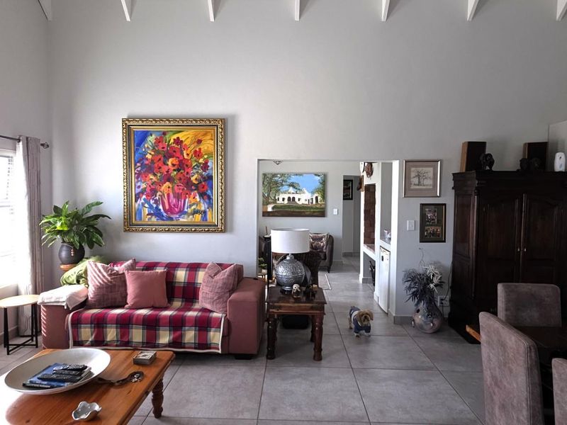 Spacious open-plan living area featuring high vaulted ceilings with exposed rafters, tiled flooring, and a modern integrated kitchen section.