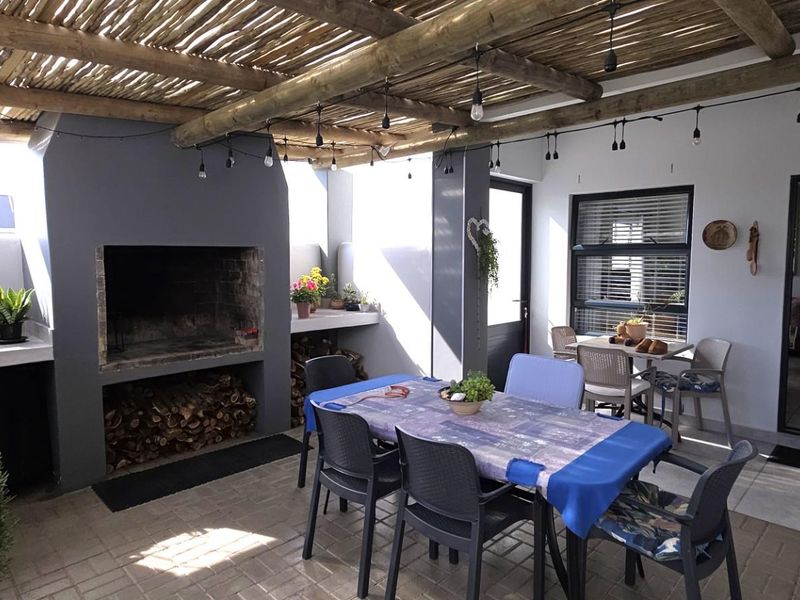 Covered outdoor patio featuring a built-in braai, concrete prep area, and rustic thatched roof, ideal for alfresco dining and entertaining.