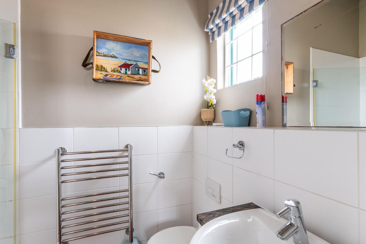 A clean and functional bathroom featuring a glass shower enclosure, vanity basin with chrome mixer tap, and a wall-mounted heated towel rail.
