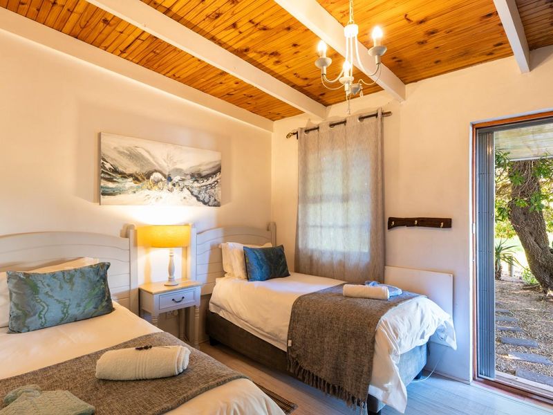 A cozy bedroom featuring a warm timber-beamed ceiling, neutral walls, and a sliding glass door providing direct access to the garden area.