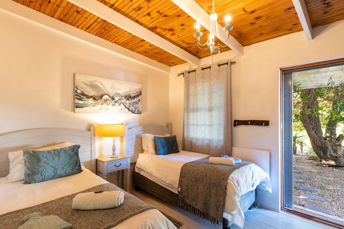 A cozy bedroom featuring a warm timber-beamed ceiling, neutral walls, and a sliding glass door providing direct access to the garden area.