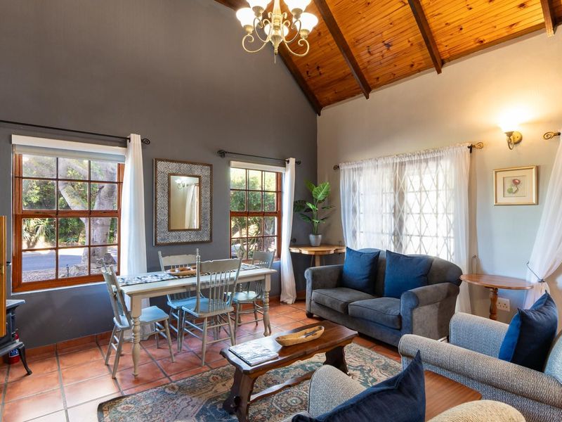 Spacious open-plan living and dining area featuring a high vaulted timber ceiling, terracotta tiled flooring, and large windows providing natural light.