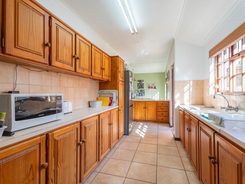 A functional galley-style kitchen featuring extensive timber cabinetry, tiled splashbacks, and a double bowl sink with ample counter space.
