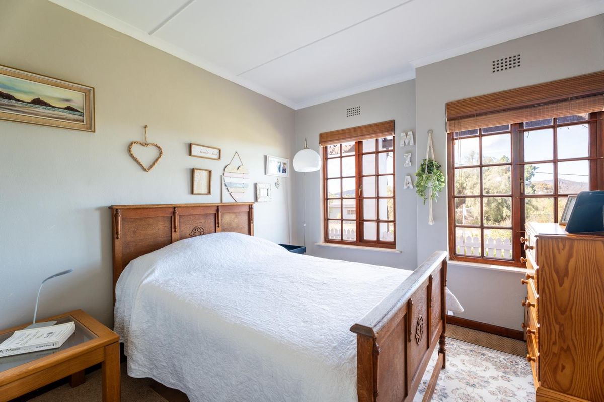 A well-lit bedroom featuring timber-framed windows, neutral wall tones, and classic cornicing, offering a comfortable and inviting living space.
