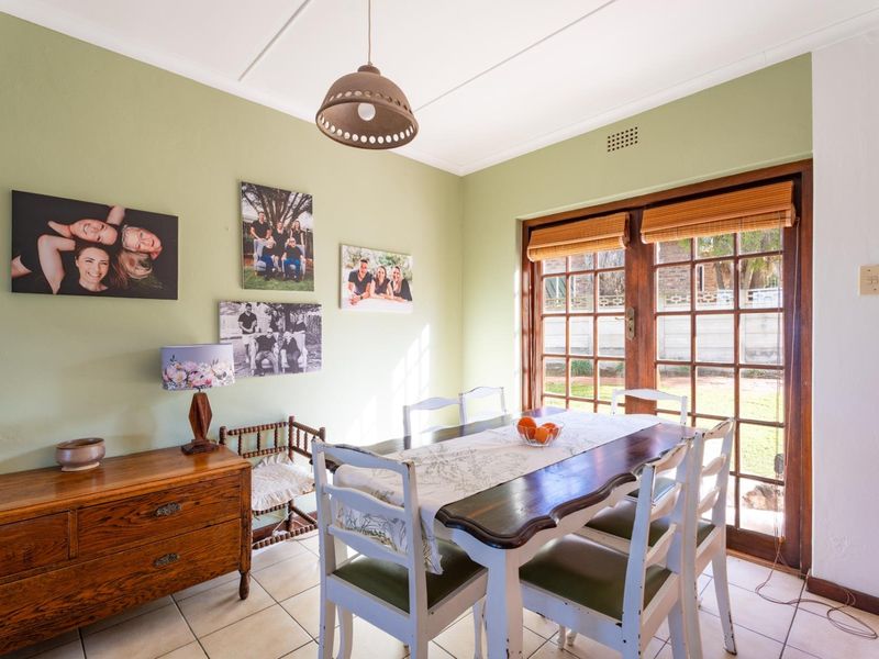 A bright dining room featuring tiled flooring and timber-framed glass doors that provide direct access to the garden area.