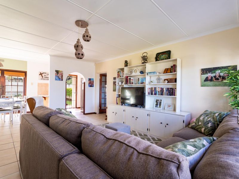 Open plan living area featuring tiled flooring, a built-in media shelving unit, and an archway leading to an adjacent dining space.