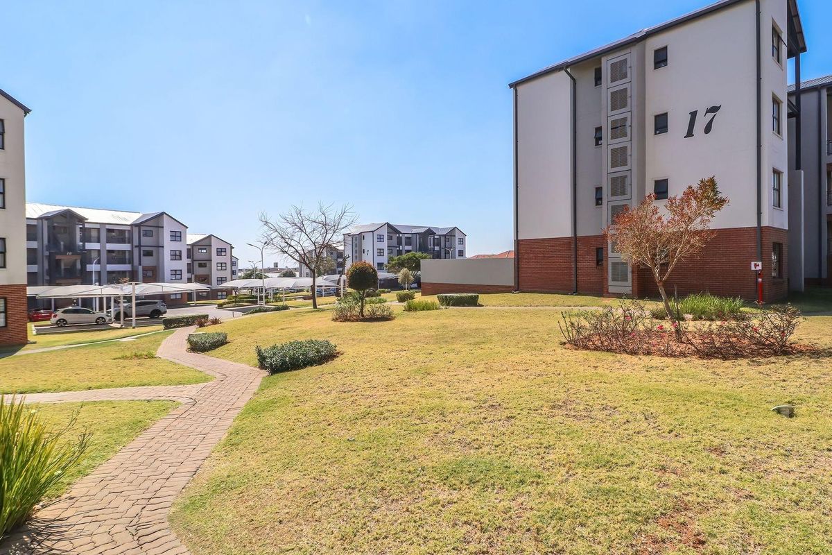 A view of the apartment complex grounds featuring well-maintained lawns, paved walkways, and multi-story residential buildings with covered parking.
