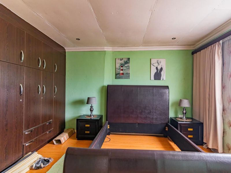 A bedroom featuring built-in dark wood cabinetry, laminate flooring, and recessed lighting, requiring cosmetic updates to the walls and ceiling.