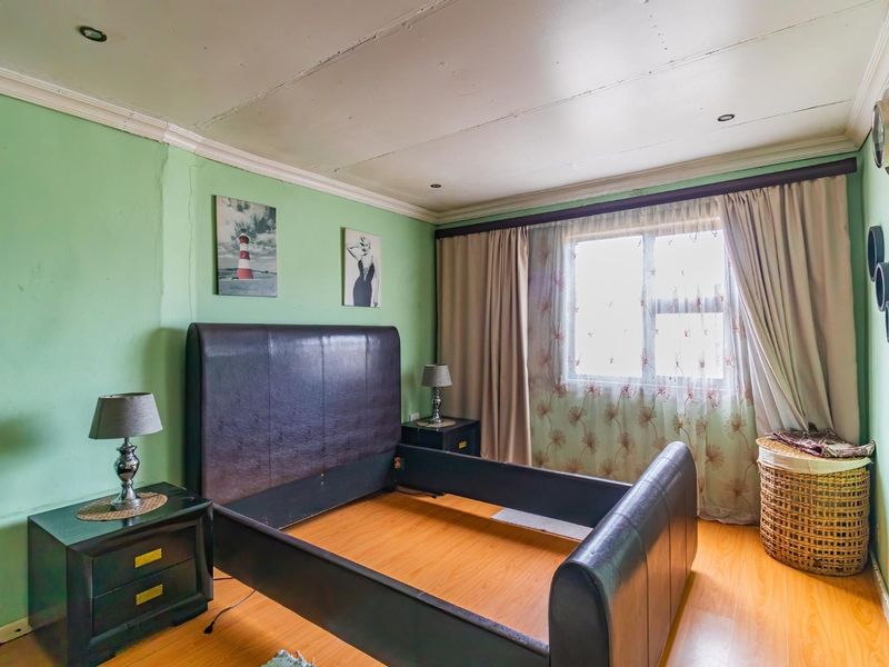A bedroom featuring laminate flooring, recessed lighting, and decorative cornice, requiring cosmetic updates to the ceiling and wall finishes.