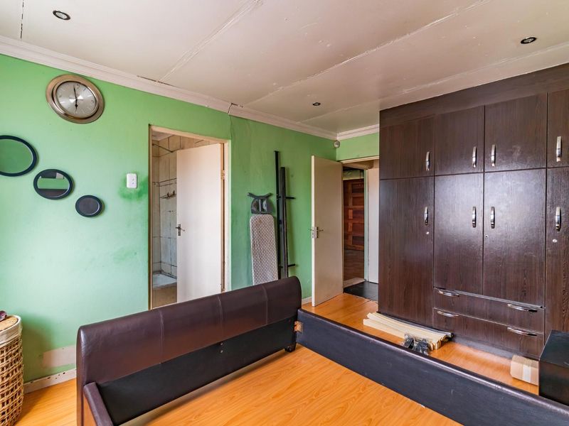 Bedroom featuring laminate flooring, built-in dark wood cupboards, and recessed lighting, requiring cosmetic updates to the walls and ceiling.
