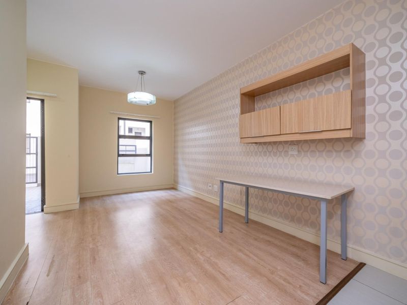 A bright, empty office space featuring laminate flooring, built-in wall cabinetry, and a modern pendant light fixture.