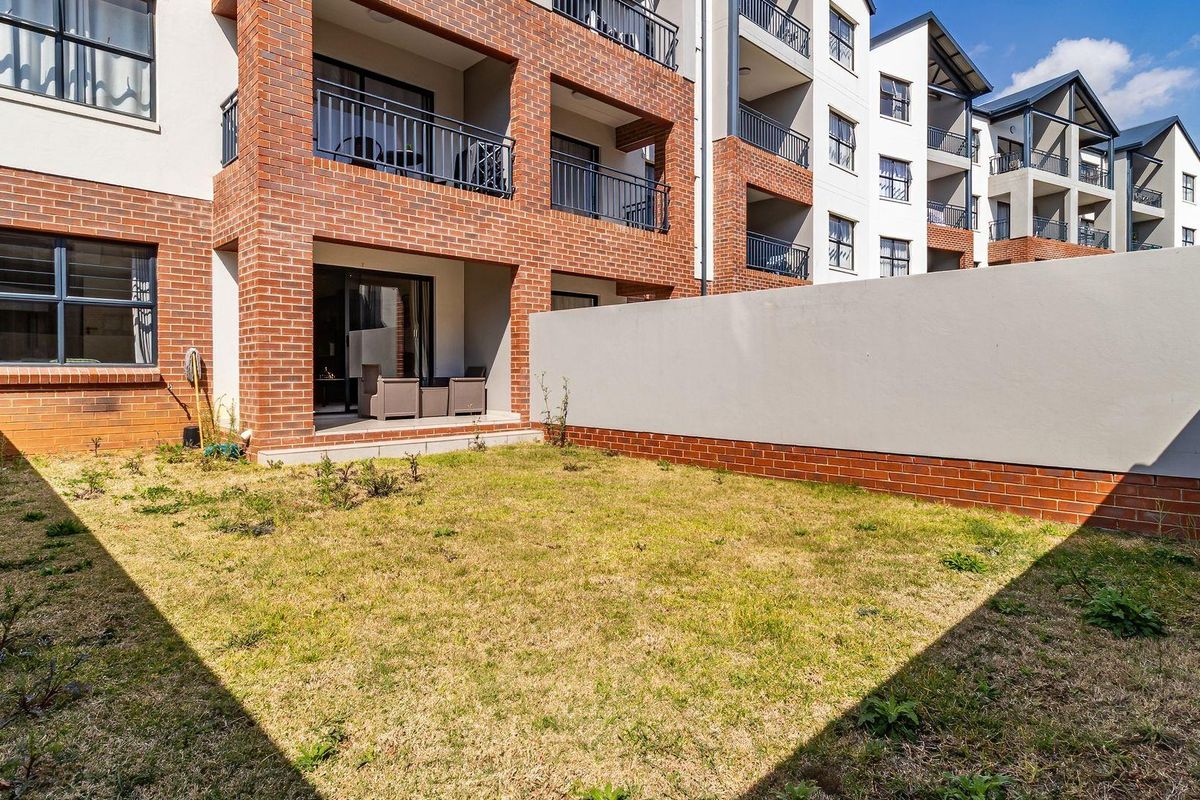 Ground floor apartment featuring a private garden, brick facade, and a covered patio area with metal railings.