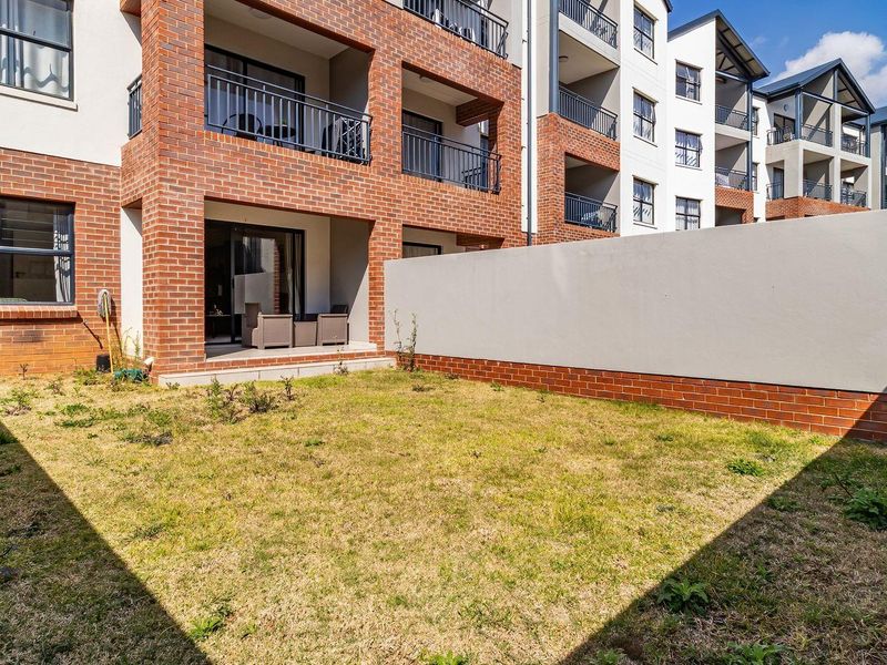 Ground floor apartment featuring a private garden, brick facade, and a covered patio area with metal railings.